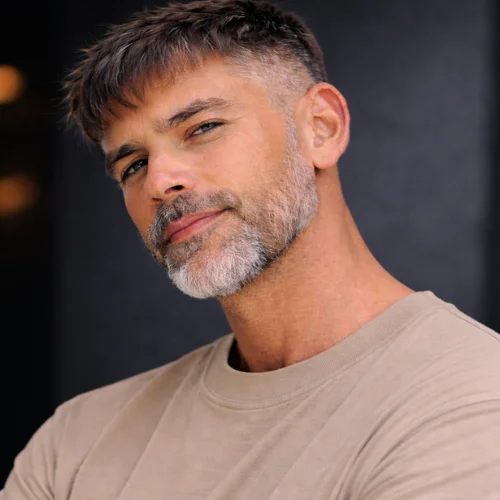 French crop mid taper haircut for men with short textured top, natural gray beard and mature modern look