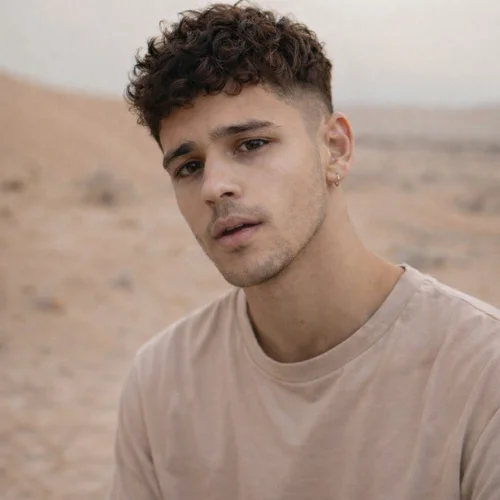 curly textured french crop haircut on young man in desert with natural volume