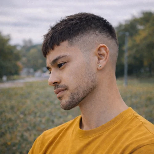 High Taper Fade French Crop haircut on young man wearing yellow shirt in hotel setting